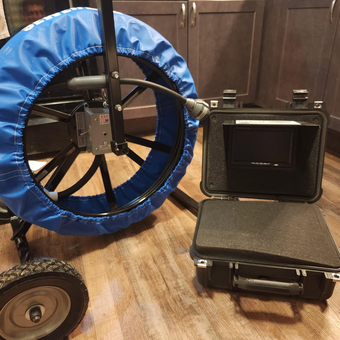 A sectional drain cleaning machine and its case, set up indoors ready for a job